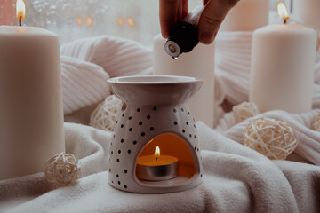 Aroma lamp with essential oil, aromatherapy at home, burning candle, dropping essential oil. Concept of home relaxation and anti stress. Natural Spa treatment Home fragnance at cozy home on the