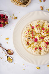 Plate of tasty Tahini halva with pistachios on light background, closeup
