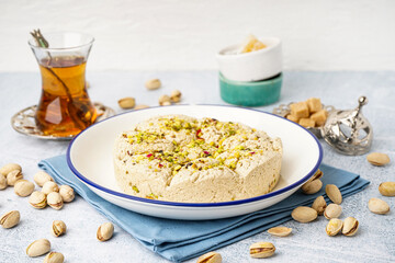 Plate of tasty Tahini halva with pistachios on light background