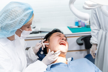 Fototapeta premium Caucasian dentist examine tooth for young man patient at dental clinic. 
