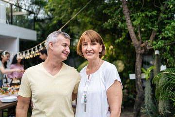 Obraz premium Portrait of senior couple looking at camera while having party outdoor. 