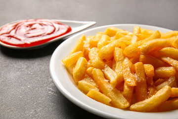 Plate with tasty french fries and ketchup on dark background, closeup