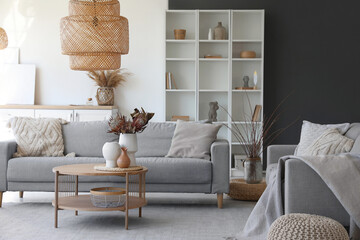 Cozy grey sofa and coffee table with bouquet of dried protea flowers in living room