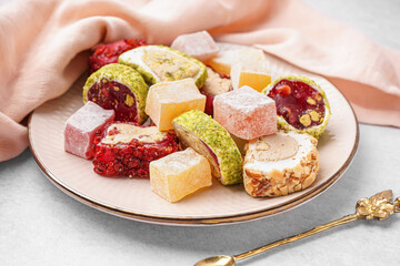 Plate with tasty Turkish Delight on light background