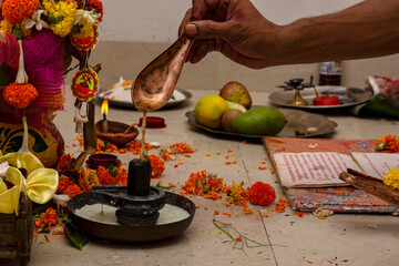 A hindu priests offering milk to Shiva linga on the occasion of an individual's first time entering...