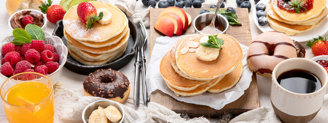 Pancakes with fresh fruits, donuts and coffee on a white background.