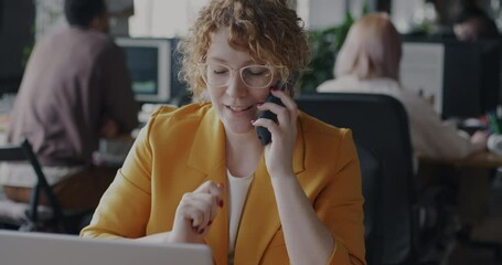 Portrait of happy employee consulting client on mobile phone and using laptop in shared office. Business communication and professional conversation concept.