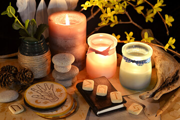 Esoteric and occult still life with vintage magic objects, runes and burning candles on witch table...