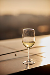 a glass of champagne on the table against the background of the sunset. a glass of sparkling champagne stands on a table in a restaurant at sunset in summer