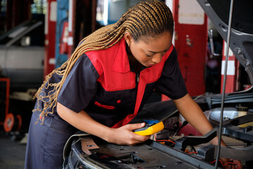 One Black female professional automotive mechanical worker checks an EV car battery and hybrid engine at a maintenance garage, expert electric vehicle service, and fixing occupations auto industry.