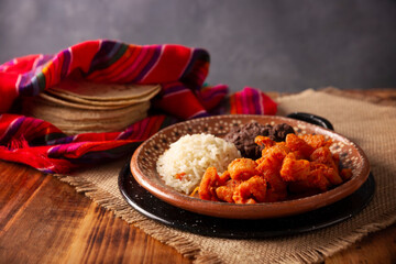 Pork rinds stewed in red sauce accompanied by rice and refried beans. Traditional homemade dish very popular in Mexico, this dish is part of the popular Tacos de Guisado.