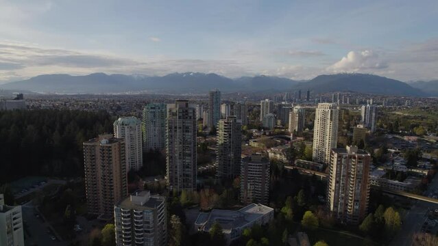 Aerial pan of residential towers with mountains in the background near Vancouver, BC