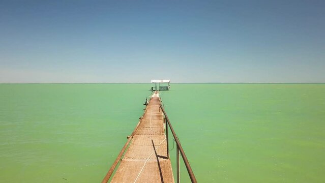 Drone flying towards cabin along the pier at Shaykhon Tudakal Lake in Uzbekistan