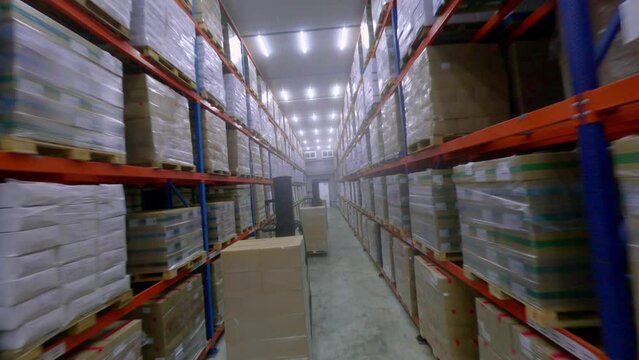 FPV drone between high multi-storey shelves in frozen food storage warehouse