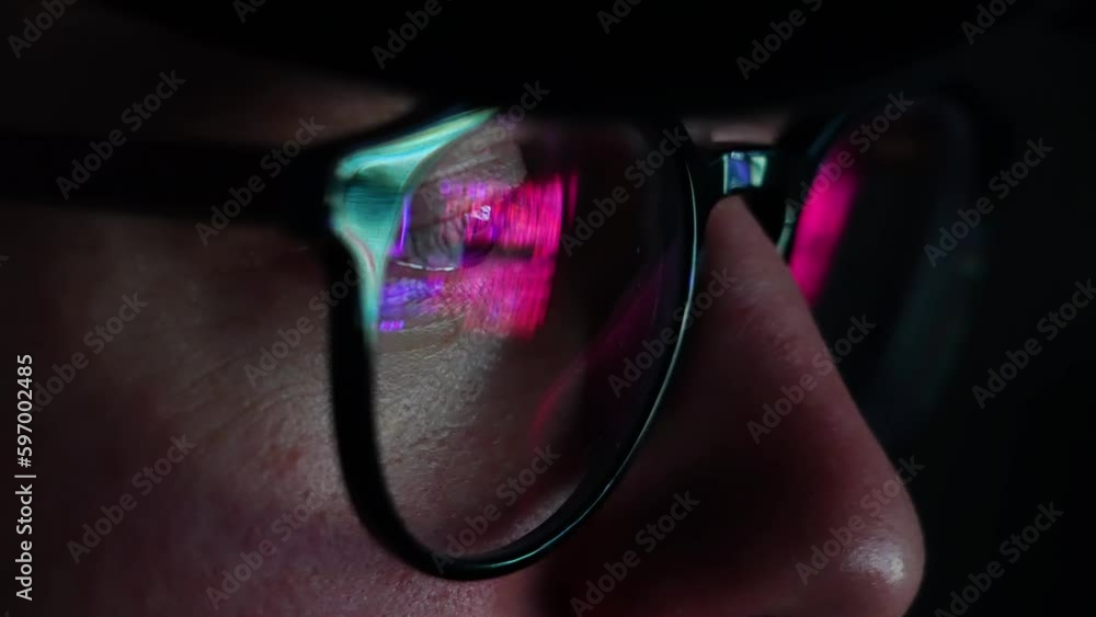 Poster hacker man with neon lights on glasses, while working on computer