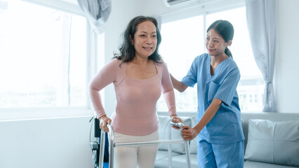 Asian Chinese female physiotherapist caregiver helping elderly woman exercise for recovery, prevention of osteoarthritis and osteoporosis.