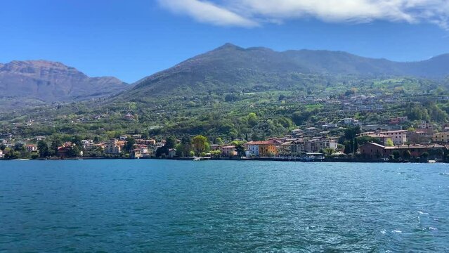 Sailing in lake Iseo with traditional Italian village in background