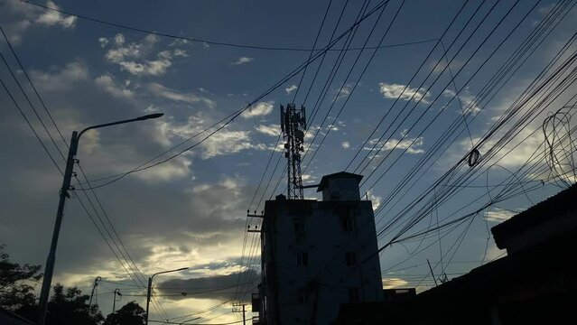 Urban city vintage vibe with dramatic sky at evening. Silhouette electric wires, network tower on building. Low angle establishing dolly shot
