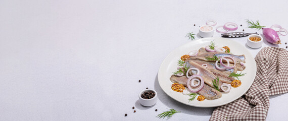 Obraz na płótnie Canvas Salted herring with dijon mustard, dill and red onion rings on white stone background