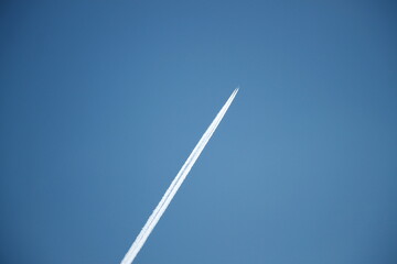 a plane with chemtrail flies over the blue sky