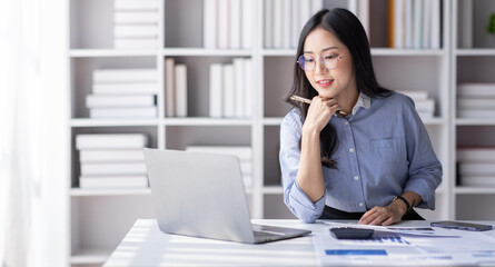 Asian Business woman using calculator and laptop for doing math finance on an office desk, tax,...