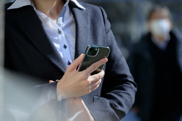 スマホを使用している女性　屋外　ビジネス　イメージ