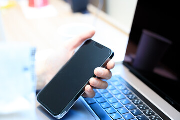 ノートパソコンとスマートフォンを使用している女性　ビジネス