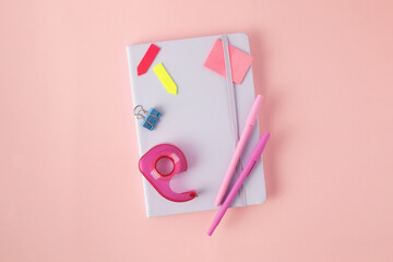Stylish flatlay of stationery, notepad and paints on a pink background. Back to school.