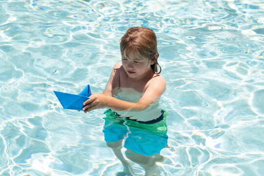 Child dreams of travel and adventure. Happy summer holidays concept. Dreams of sea, adventures and travel. Child playing with paper boat in water. Summer vacation.