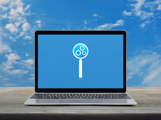 Seo icon on laptop computer monitor screen on wooden table over blue sky with white clouds, Search engine optimization concept