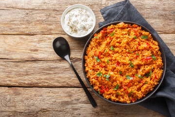 Turkish pilaf from bulgur with vegetables and spices close-up in a bowl on a wooden table....