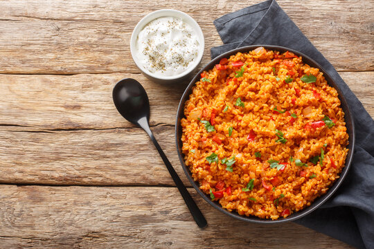 Turkish pilaf from bulgur with vegetables and spices close-up in a bowl on a wooden table. Horizontal top view from above