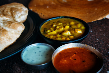 Puri bhaji and masala dosa are two of India's favorite traditional breakfast dishes in one close-up shot. Indian bread with bhadji, chutney and sambar sauces