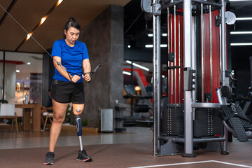 Fototapeta na wymiar Woman with prosthetic leg exercising on multistation at gym for arm and shoulders muscles