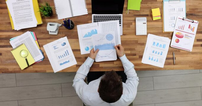 Businessman studying documents with graphs at table in office top view 4k movie. Paperwork in business financial report concept