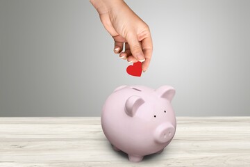 Red heart is put in a donation piggy bank