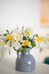 A bouquet of delicate daffodils in a vase on the background of a home interior