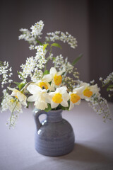 A bouquet of delicate daffodils in a vase on the background of a home interior