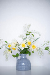 A bouquet of delicate daffodils in a vase on the background of a home interior