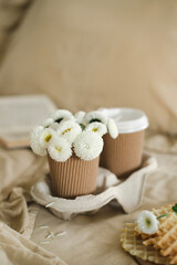 A cup of warm, warming aromatic tea, coffee, flowers nearby