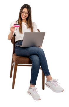 Using laptop and credit card, Caucasian brunette girl using laptop and credit card. Online shopping concept idea banner image. Isolated transparent png. Sitting on the chair. Making purchases.