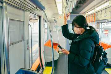 Asian woman traveler using smart phone in the subway train.