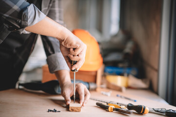 Asian carpenter working with equipment tools on wooden table in carpentry shop. Concept working of carpenter. Professional working wooden man.