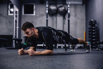 Full body burning exercise, using new EMS technology. A young attractive man in clothes for EMS is...
