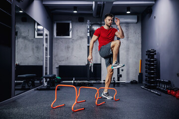 Fototapeta na wymiar High skip on warming up functional training. Warming up the muscles of the whole body and jumping sideways over obstacles. Love of sports and determination to win. Flexibility and dynamism of movement