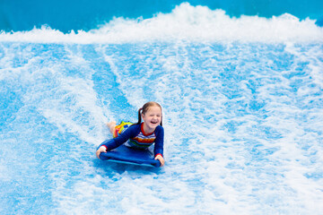 Little girl surfing in beach wave simulator