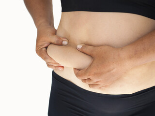 Woman pulls the hand skin showing fat in the side abdomen. the deposition of subcutaneous fat tissue. closeup photo, blurred.