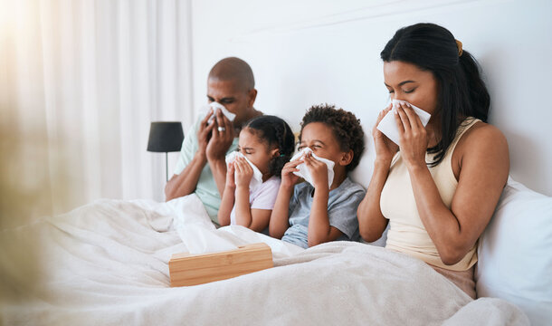 Sick, flu and family on a bed, tissue and blowing nose with illness, disease and cold at home. Parents, mother and father with siblings, children and kids in a bedroom, allergy and health issue