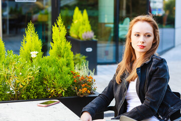 Woman wait in outdoor cafe, using cell phone