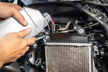 Motorcycle mechanic filling coolant,check liquid level in radiator,.change the coolant in...